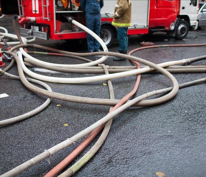 Fire truck hoses on the road after a hire has damaged a home.